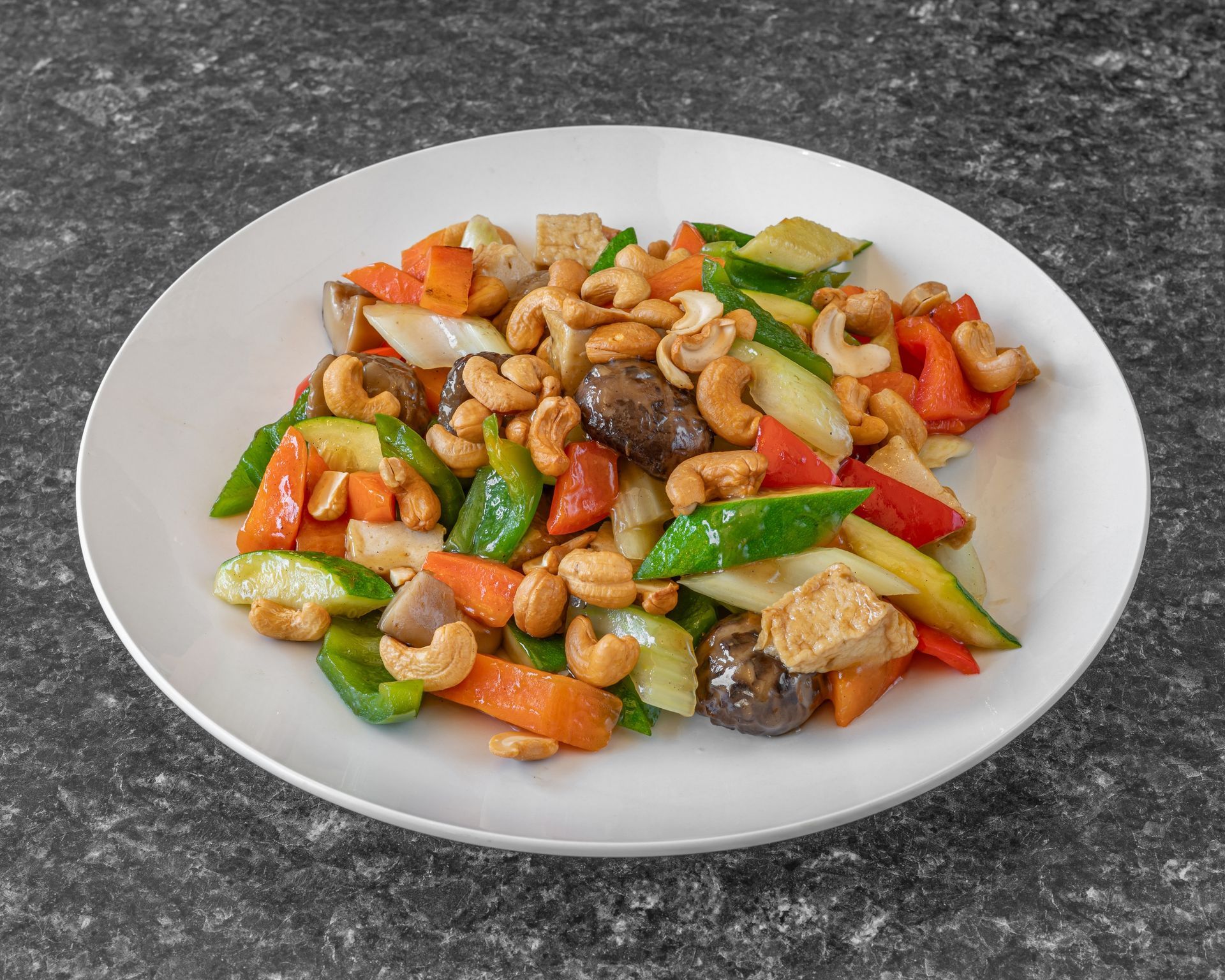 Cashew stir-fry on a white plate: colorful vegetables and nuts.