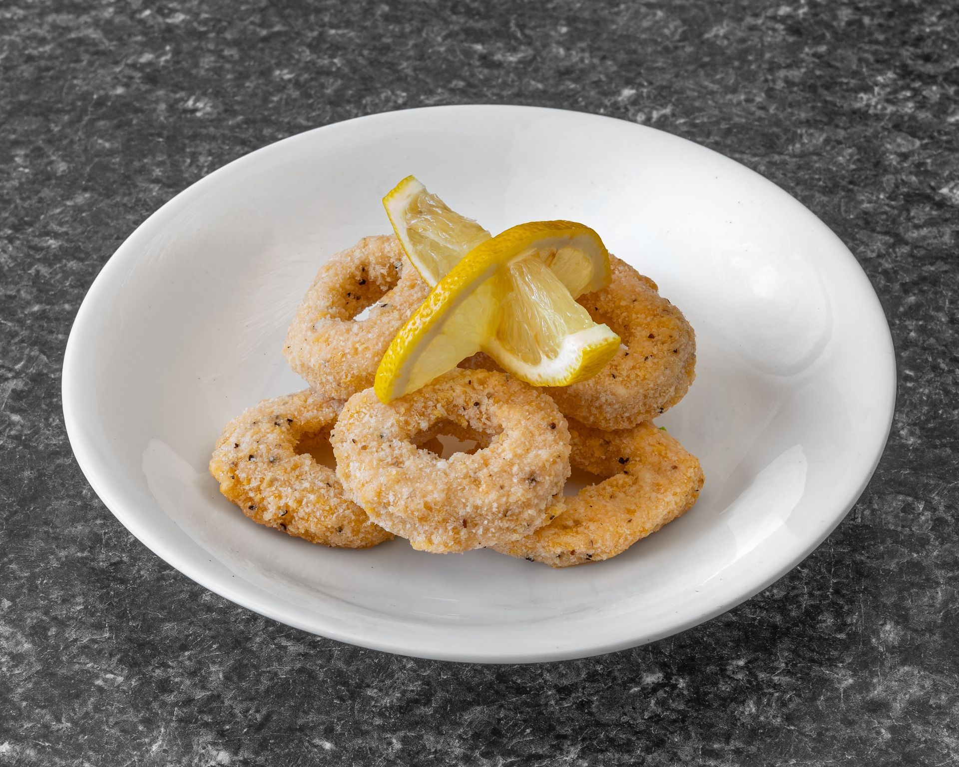Fried calamari rings with lemon wedges on a white plate.