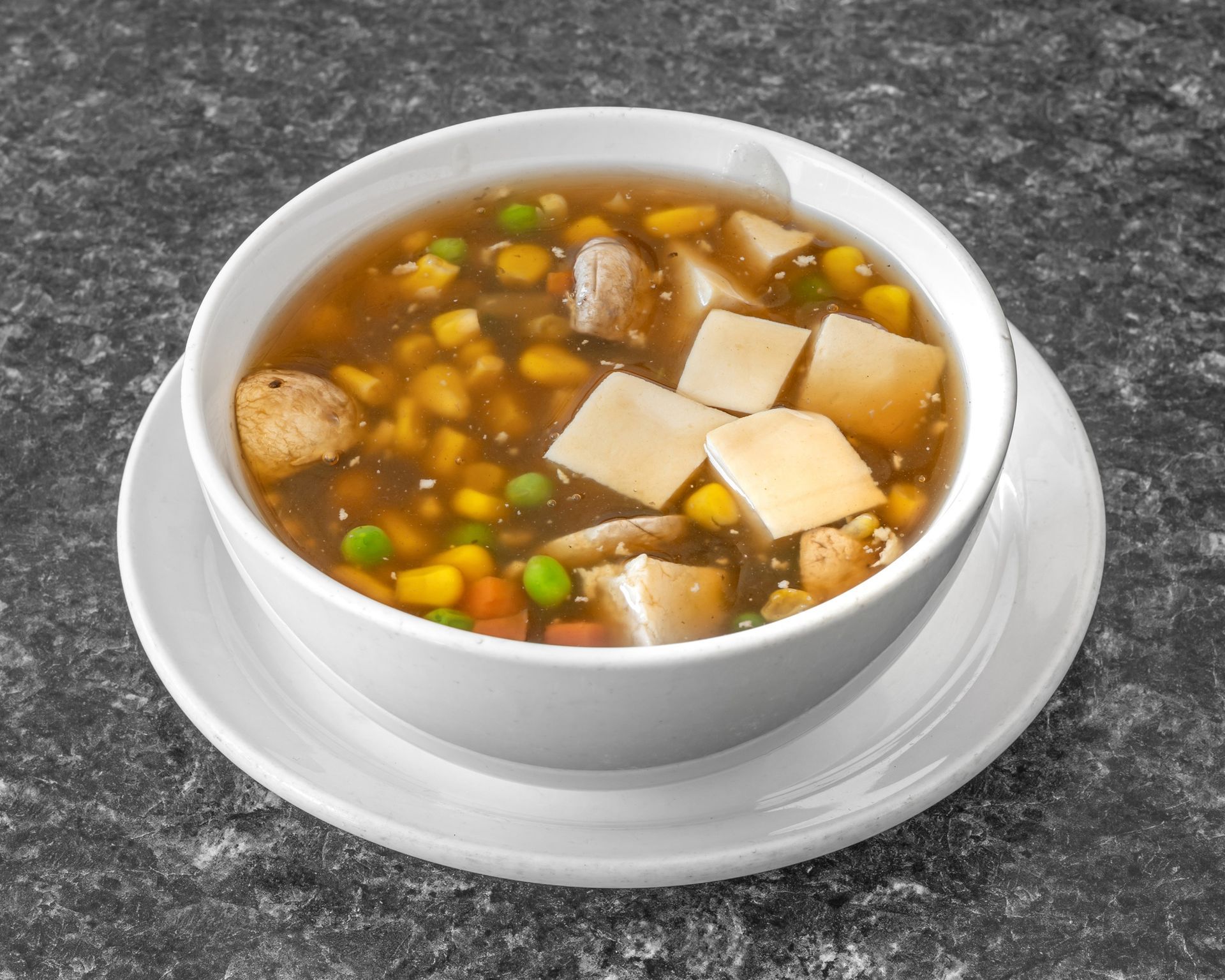 Bowl of soup with vegetables, tofu, and meat.