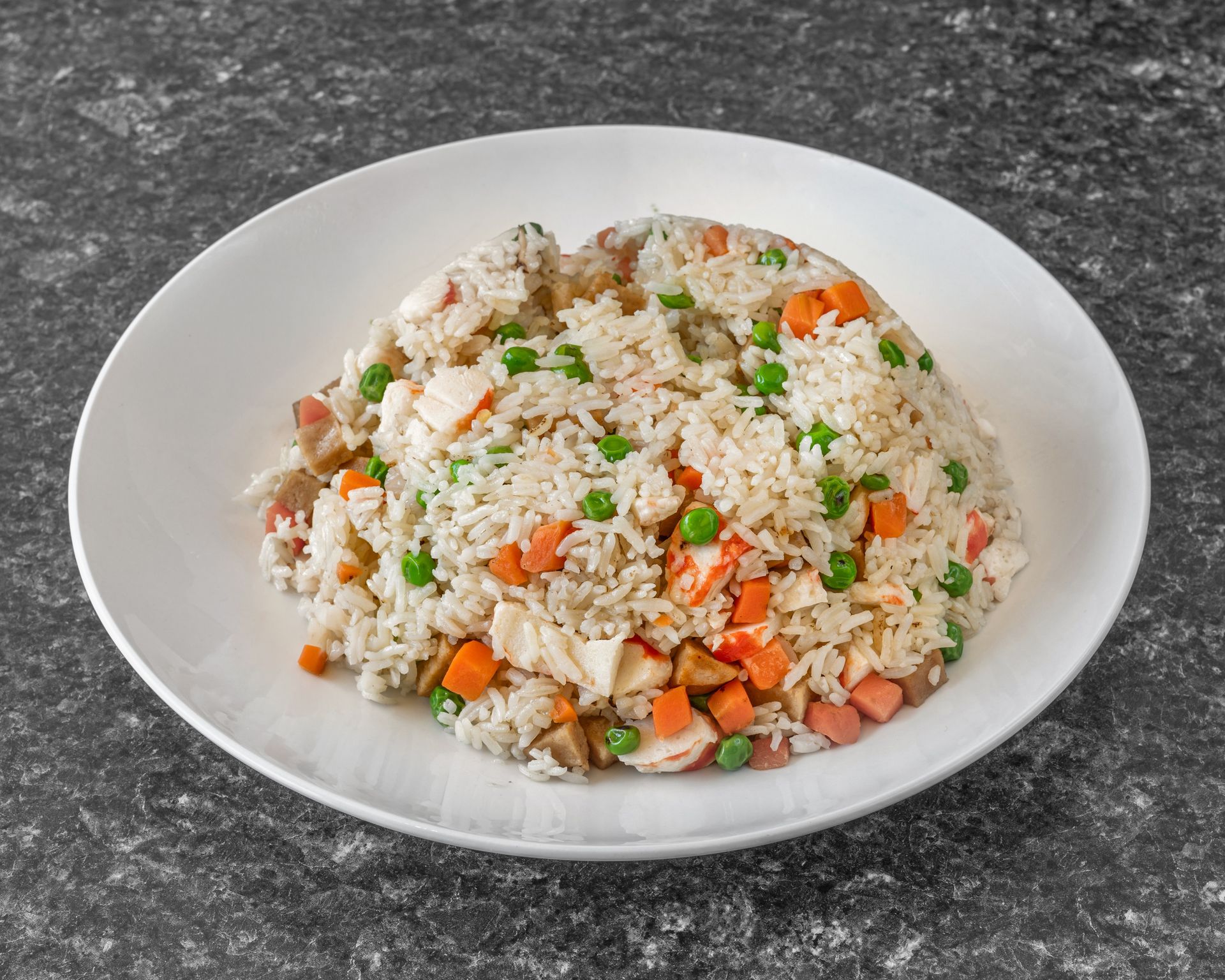 Plate of fried rice with carrots, peas, and other ingredients.