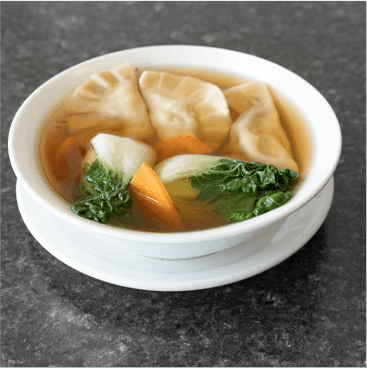 Bowl of dumpling soup with dumplings, bok choy, and carrots.