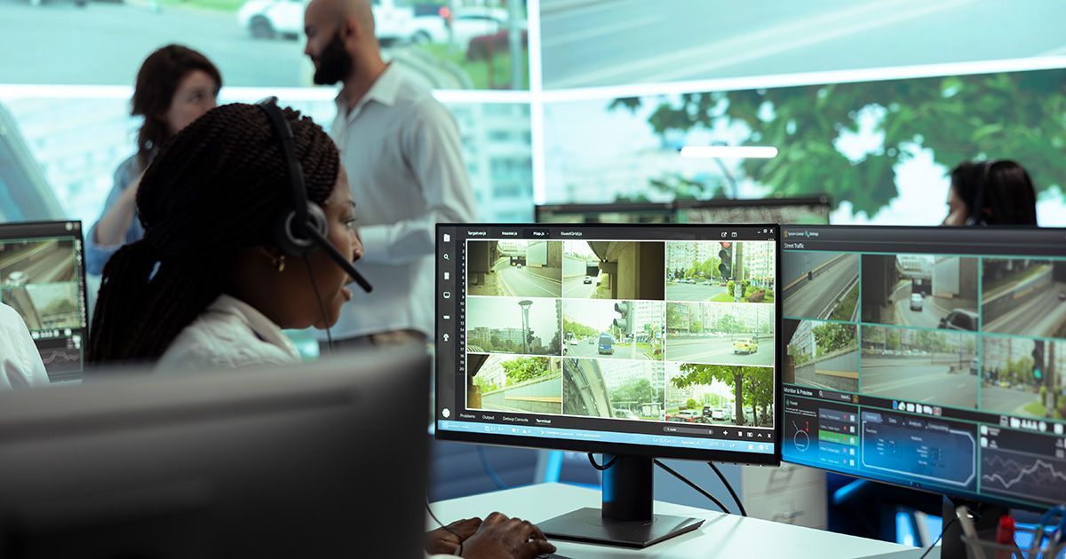 Operators monitoring security cameras on dual screens in a control room