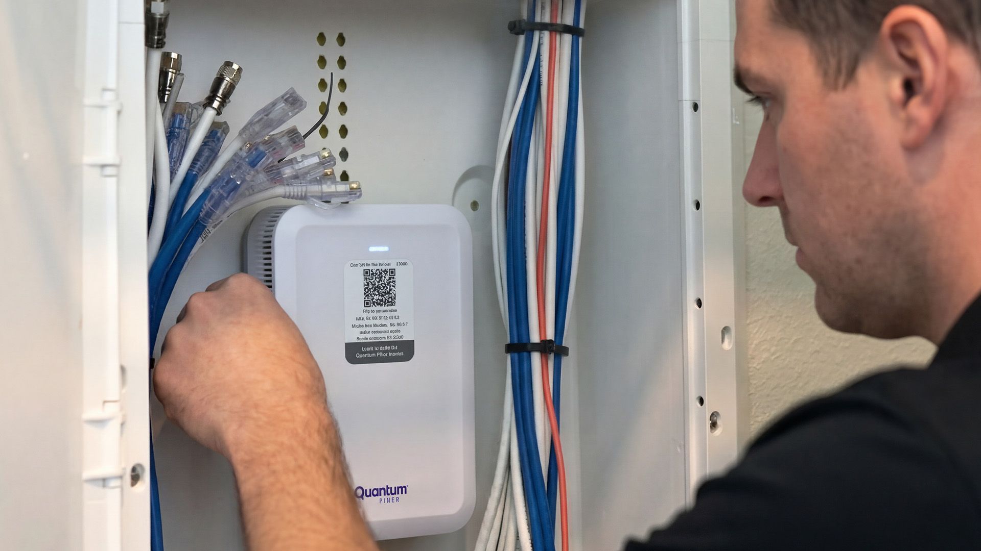 Technician connecting network cables inside a wall-mounted telecom cabinet