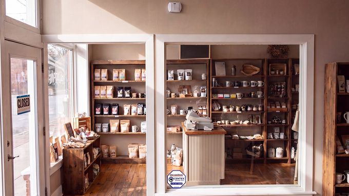 Interior view of a small shop with shelves of goods and a display counter by the window