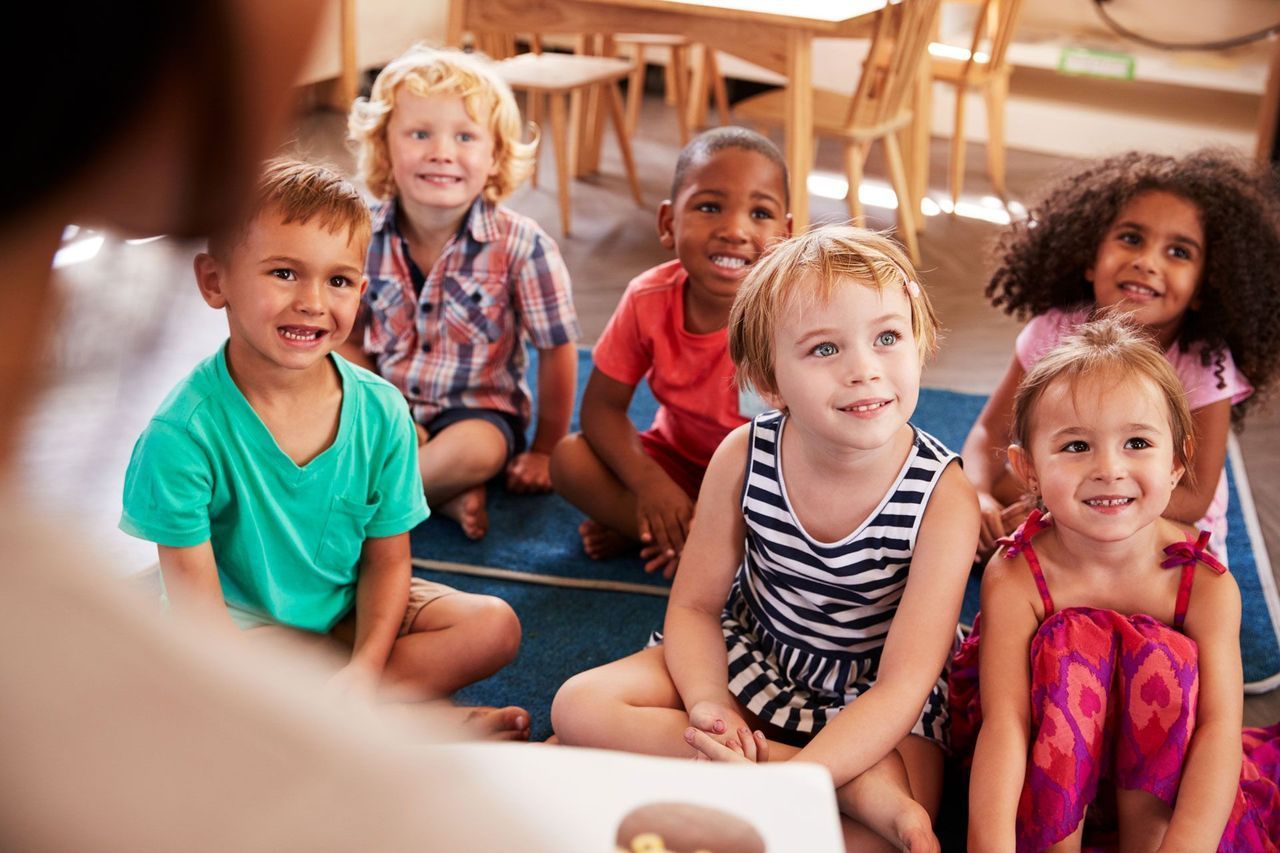 A Group of Children Sit on the Floor Listening to a Story