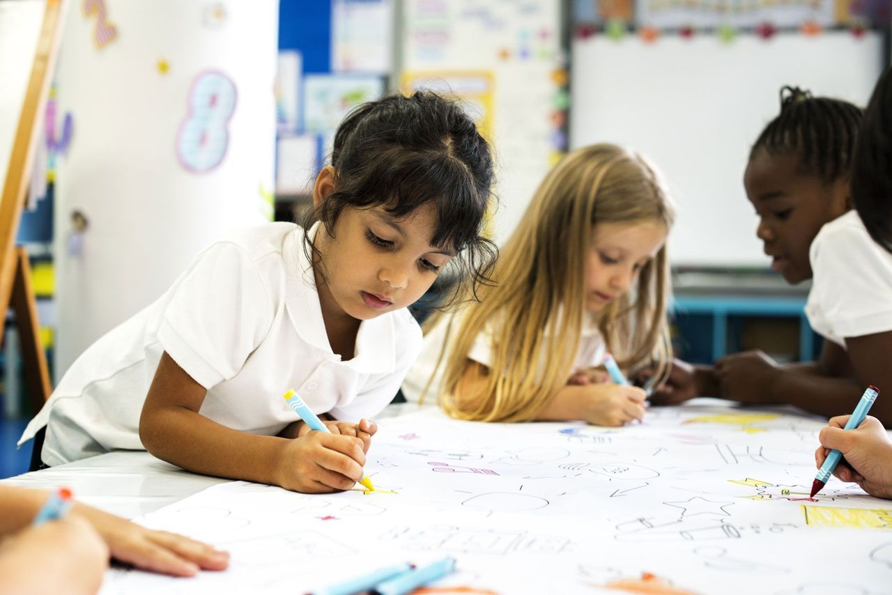 A Group of Young Girls Are Drawing on a Large Piece of Paper