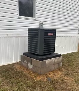 Outdoor air conditioner unit on a concrete pad beside a house with white siding.