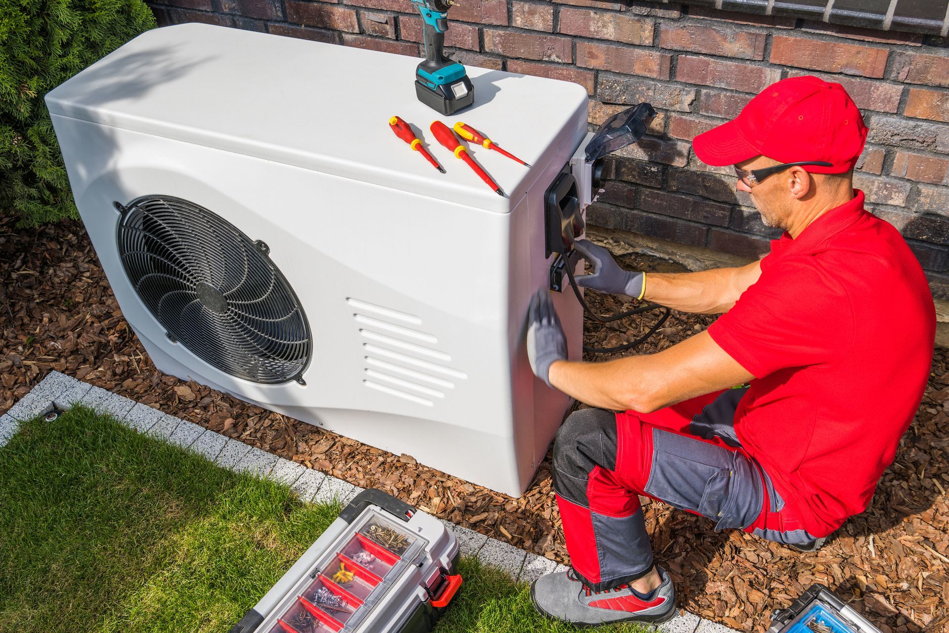 A man services an air conditioner in Phoenix, AZ, representing Hutzel & Associates, emphasizing the importance of indoor air quality testing.