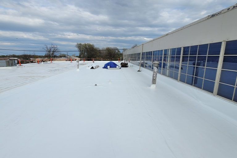 White commercial building roof with a blue tent and cloudy sky.