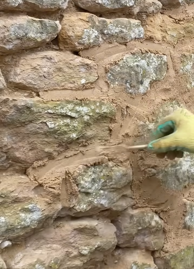 Stone wall with tuckpointing repairs in progress.