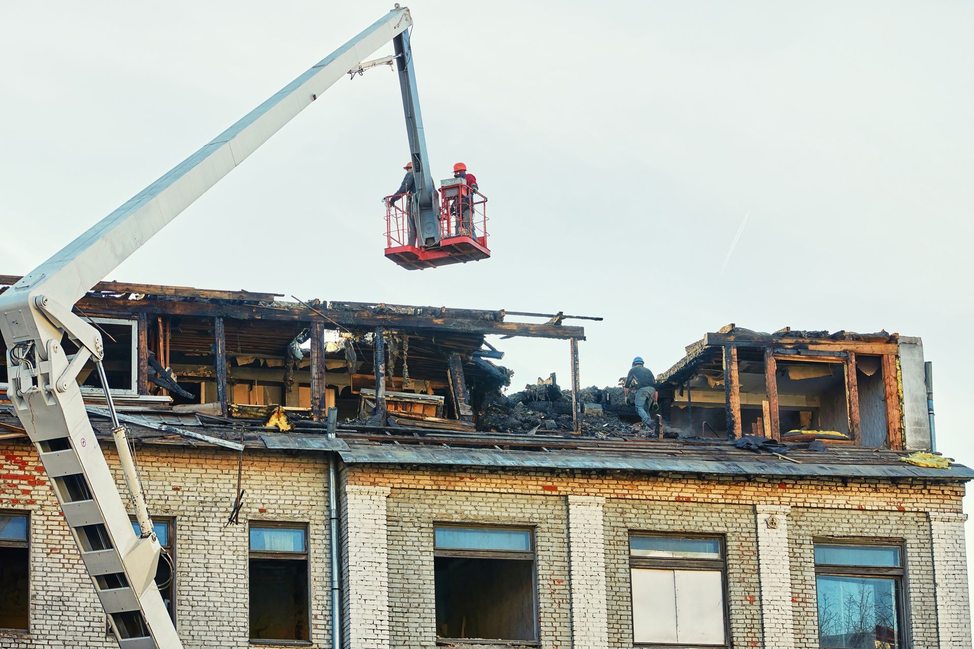 Crane lifts debris from a burned building roof during demolition