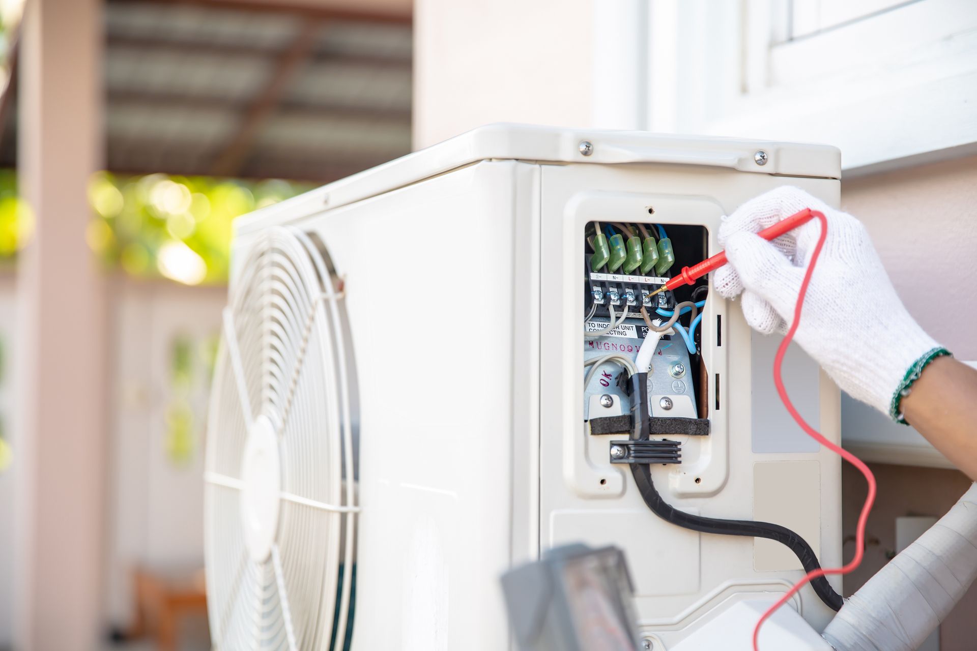 Technician testing an outdoor air conditioner unit with a multimeter. Technician testing an outdoor air conditioner unit with a multimeter.