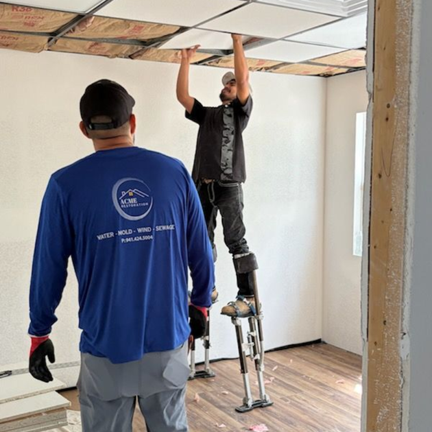 Restoration technicians repairing a water-damaged ceiling