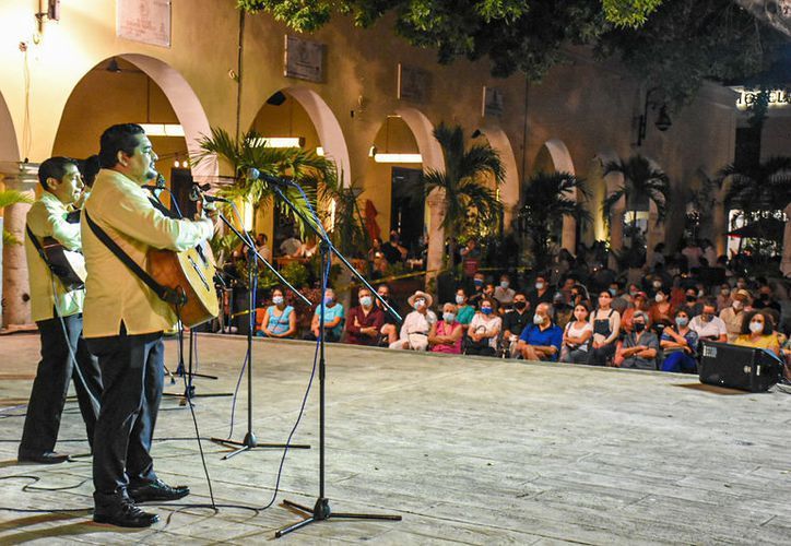 A man is playing a guitar in front of a crowd of people.