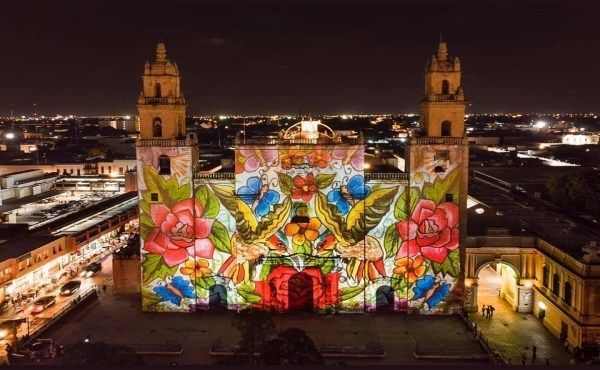 An aerial view of a church with a floral design projected on it at night