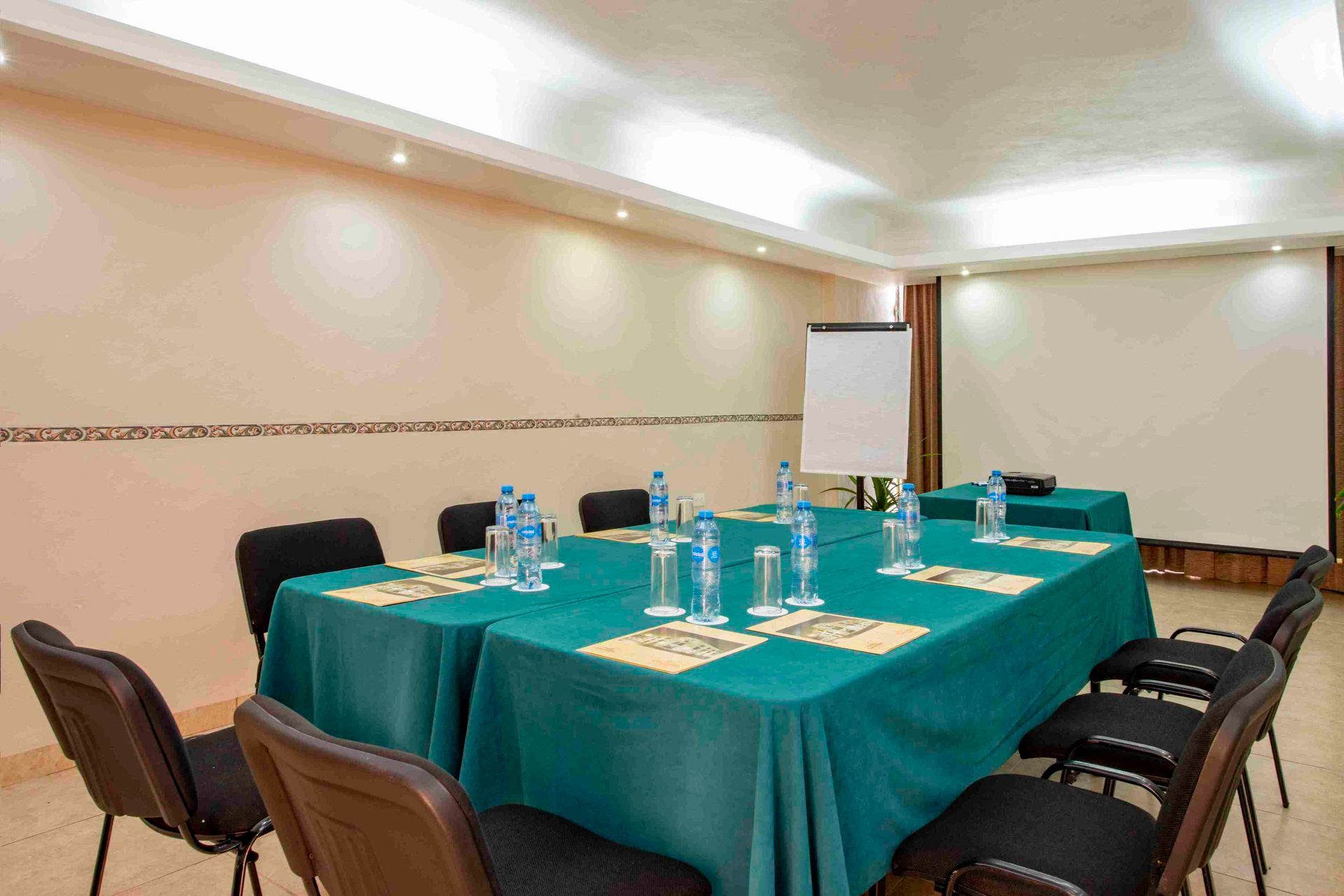 A conference room with a long table and chairs and a projector screen.