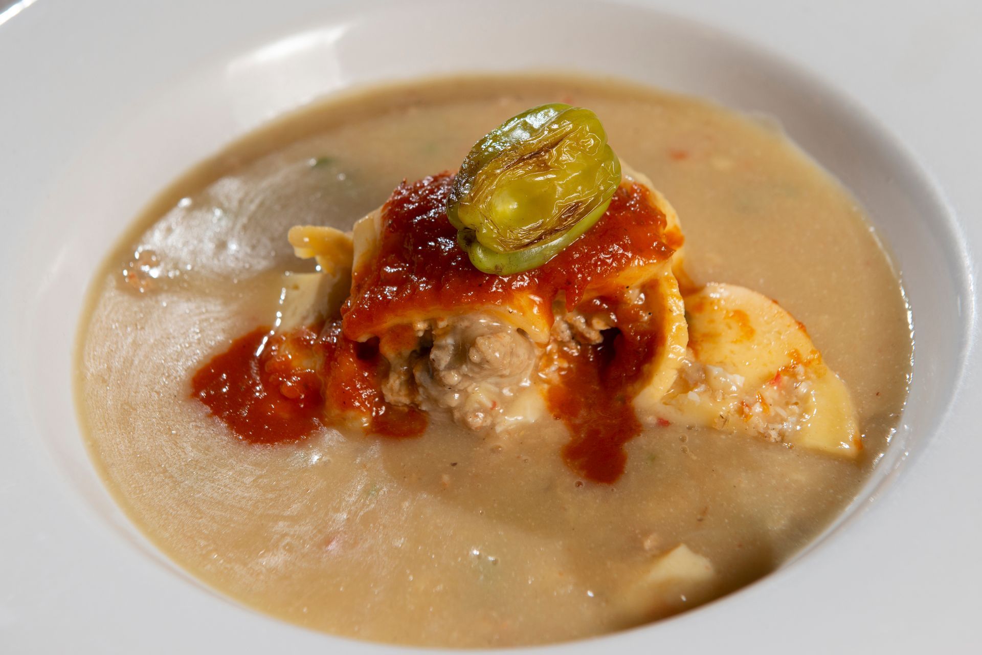A bowl of soup with a piece of lasagna on top