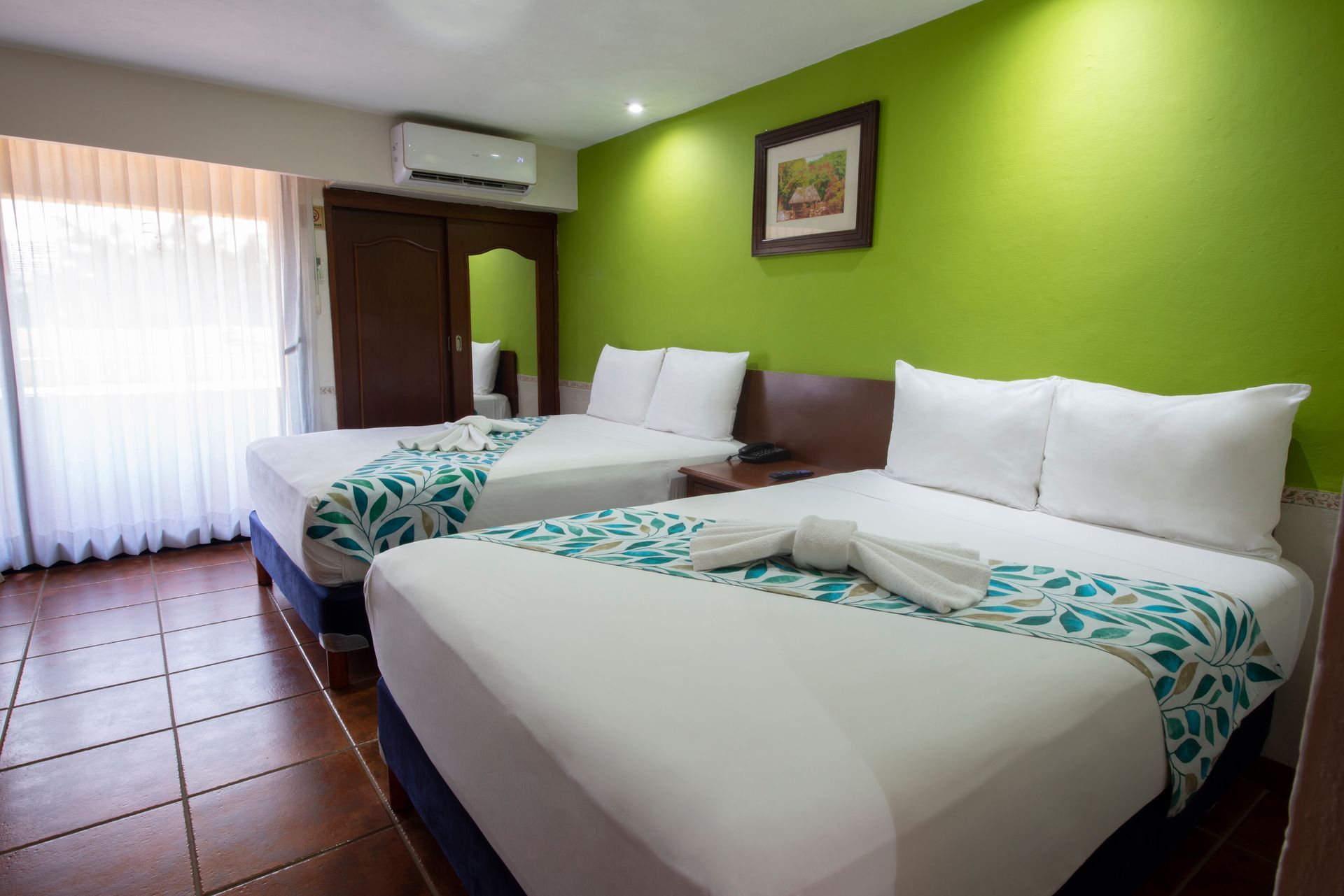 A hotel room with two beds and a green wall