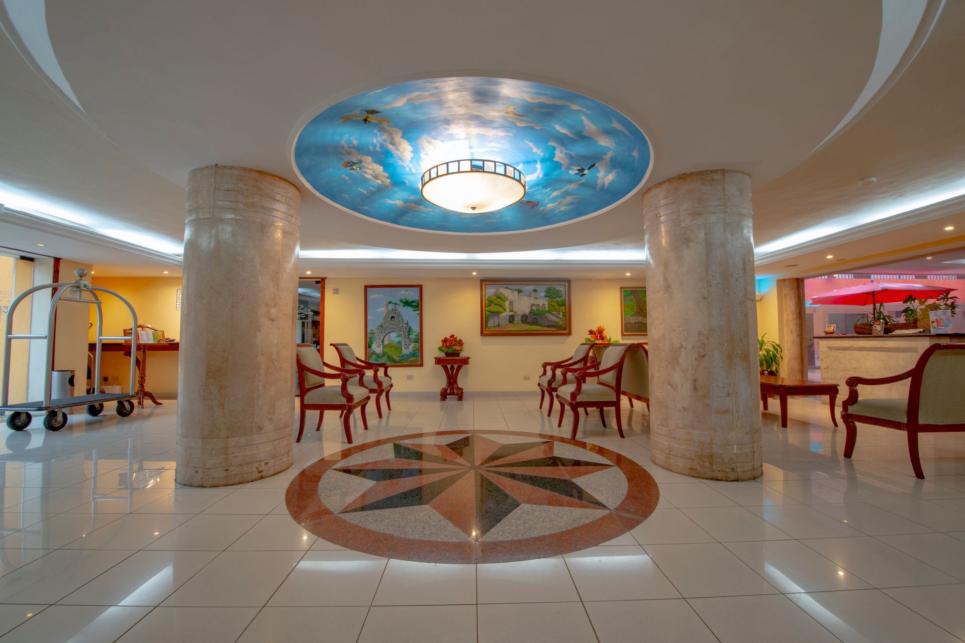 A hotel lobby with chairs and a chandelier on the ceiling.