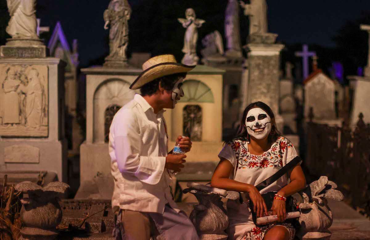A man and a woman are sitting next to each other in a cemetery.
