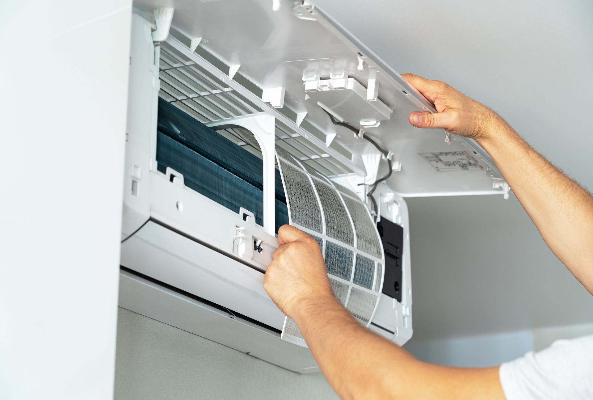 [A technician’s hands change an air conditioning filter for maintenance.