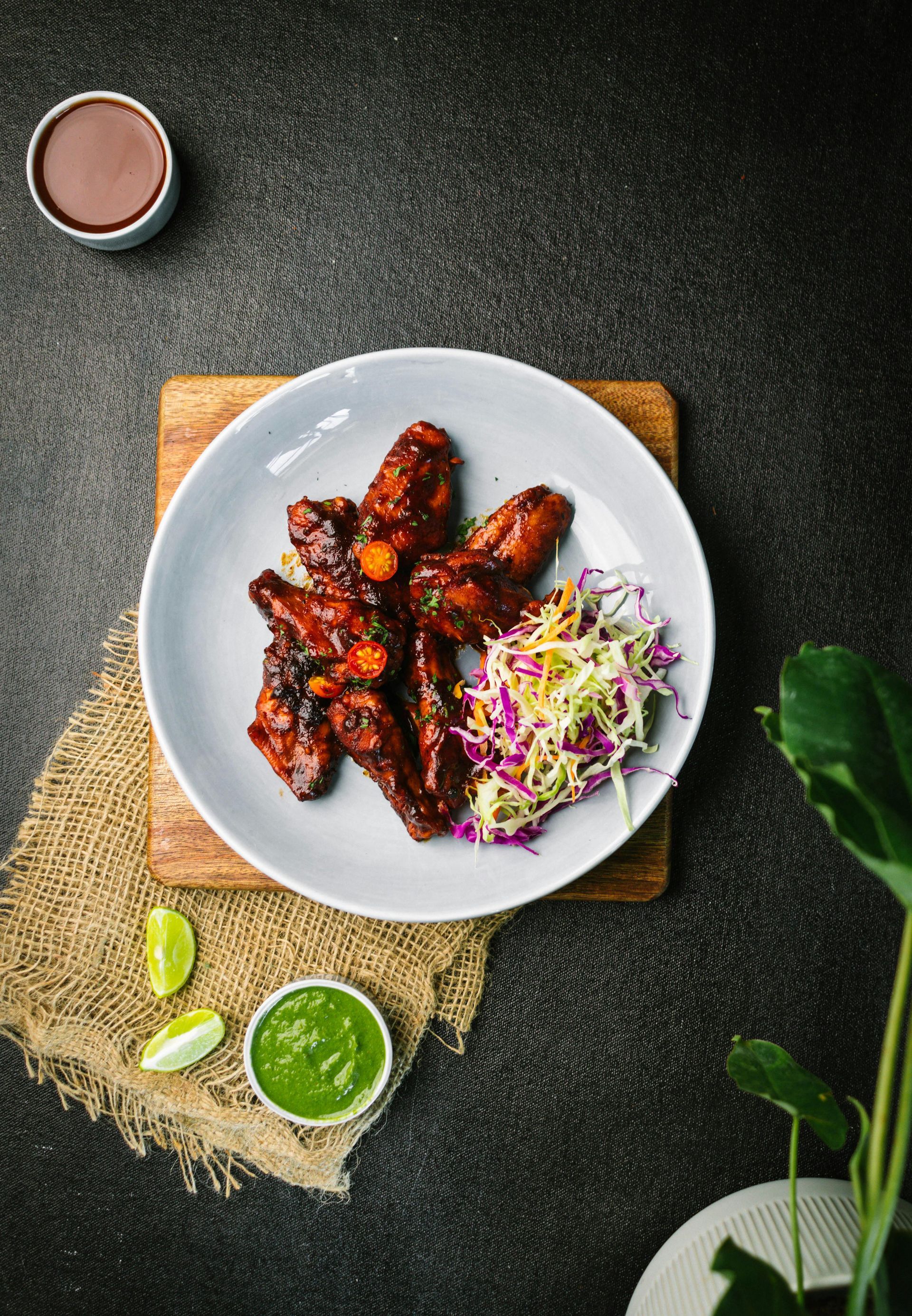 A plate of food with chicken wings and coleslaw on a table.