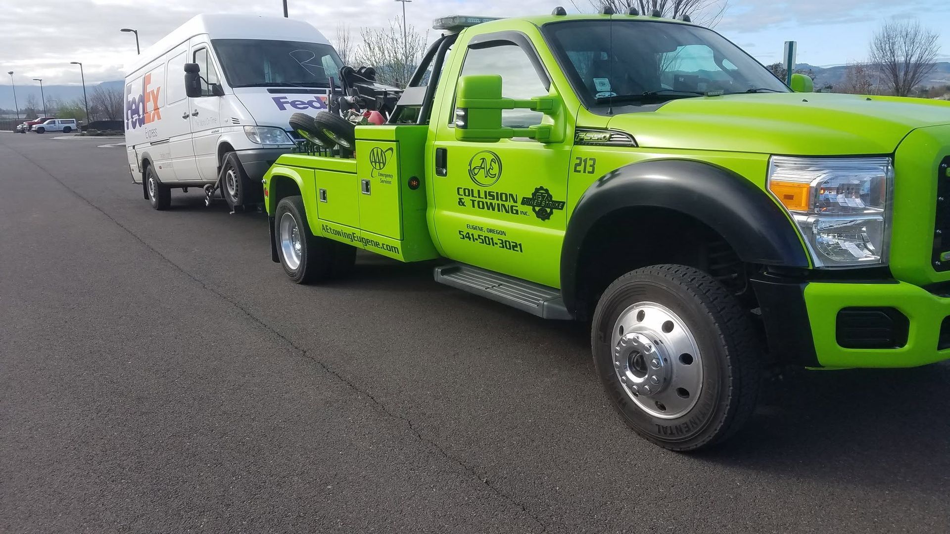 Bright green tow truck hauling a white van on a road