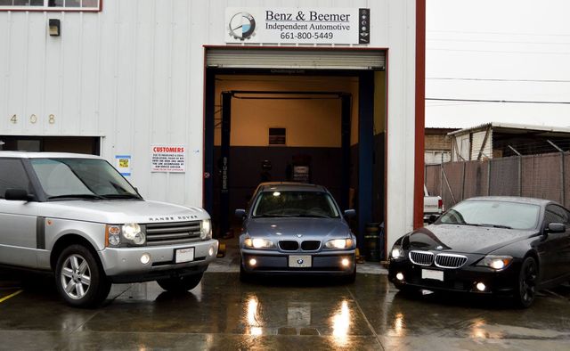 Cars outside a garage entrance on a wet day, with a black car inside and two SUVs parked at the sides