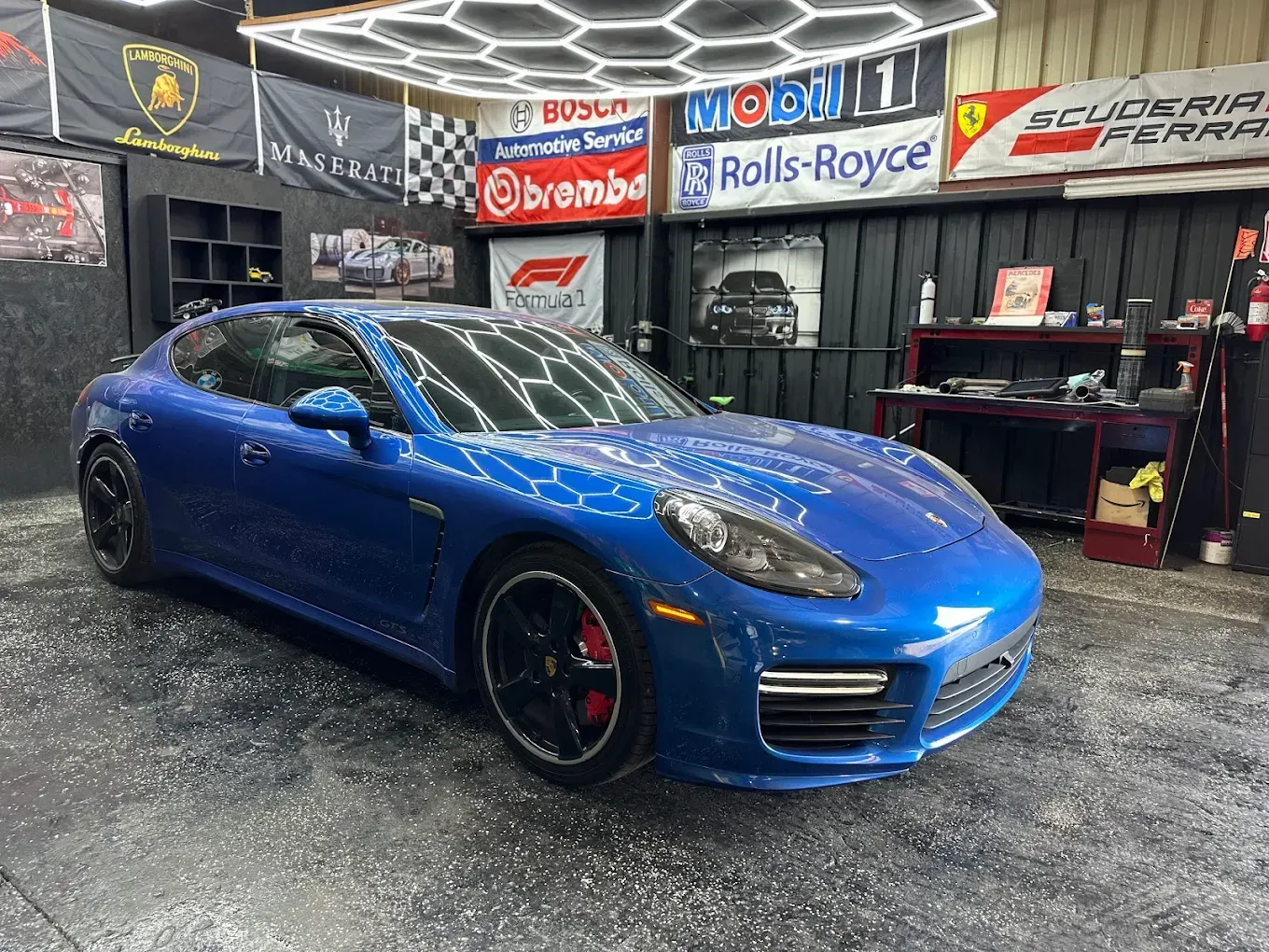 Blue sports car in a garage with racing and automotive signs on the walls