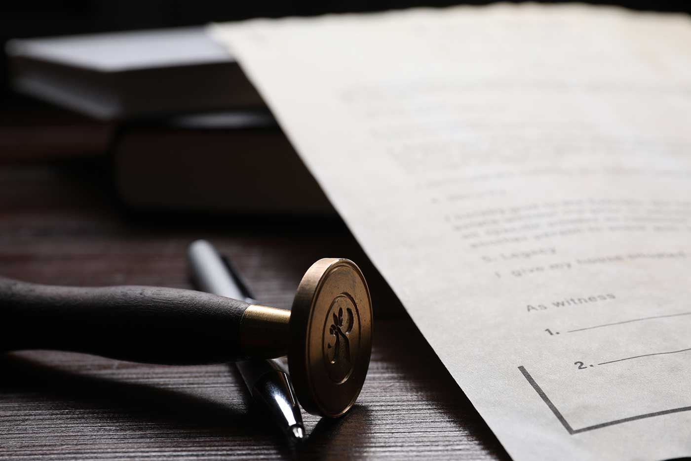 A stamp is sitting on top of a piece of paper next to a pen.