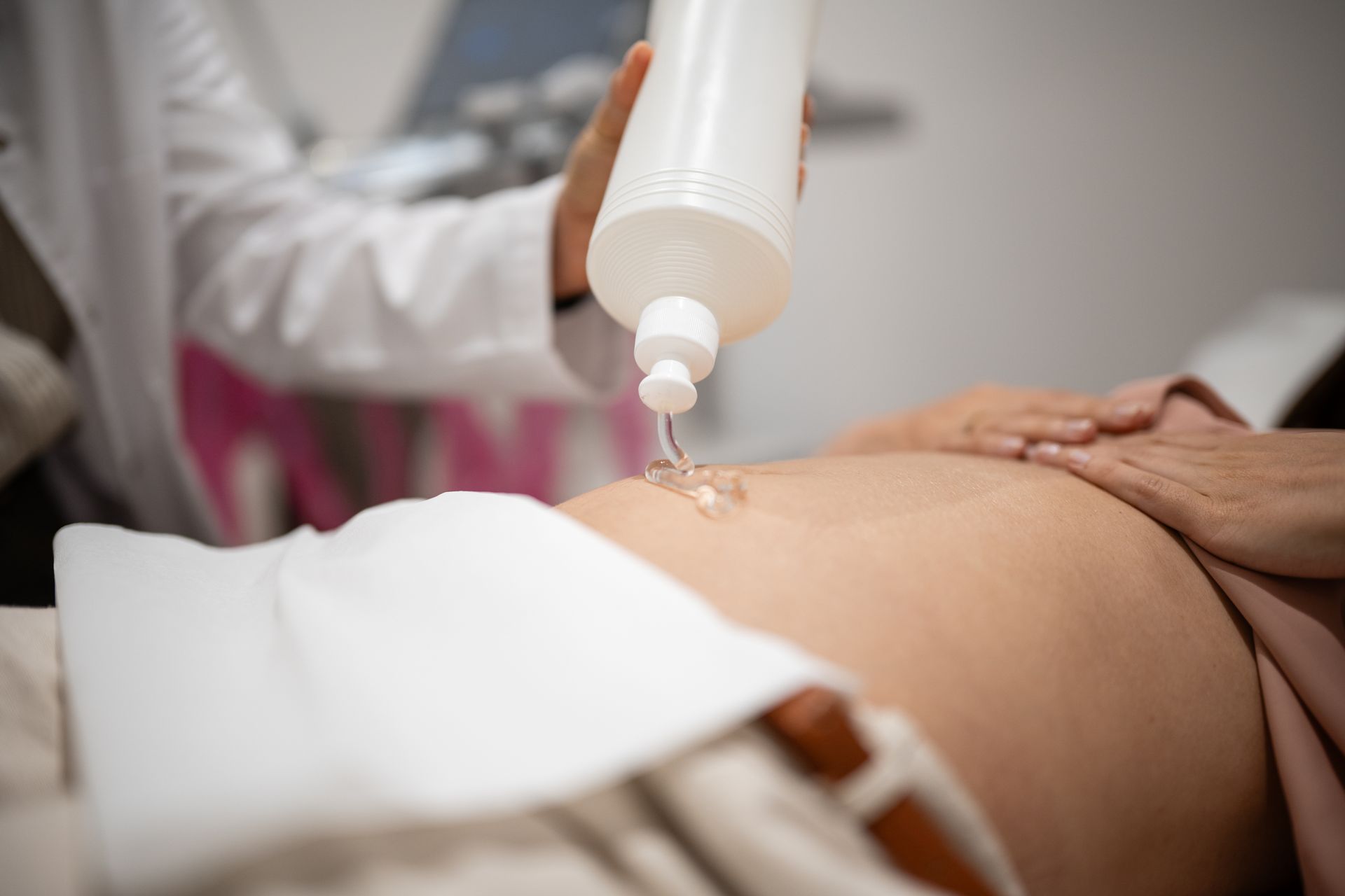 Medical professional applying ultrasound gel to a pregnant woman during a prenatal examination.