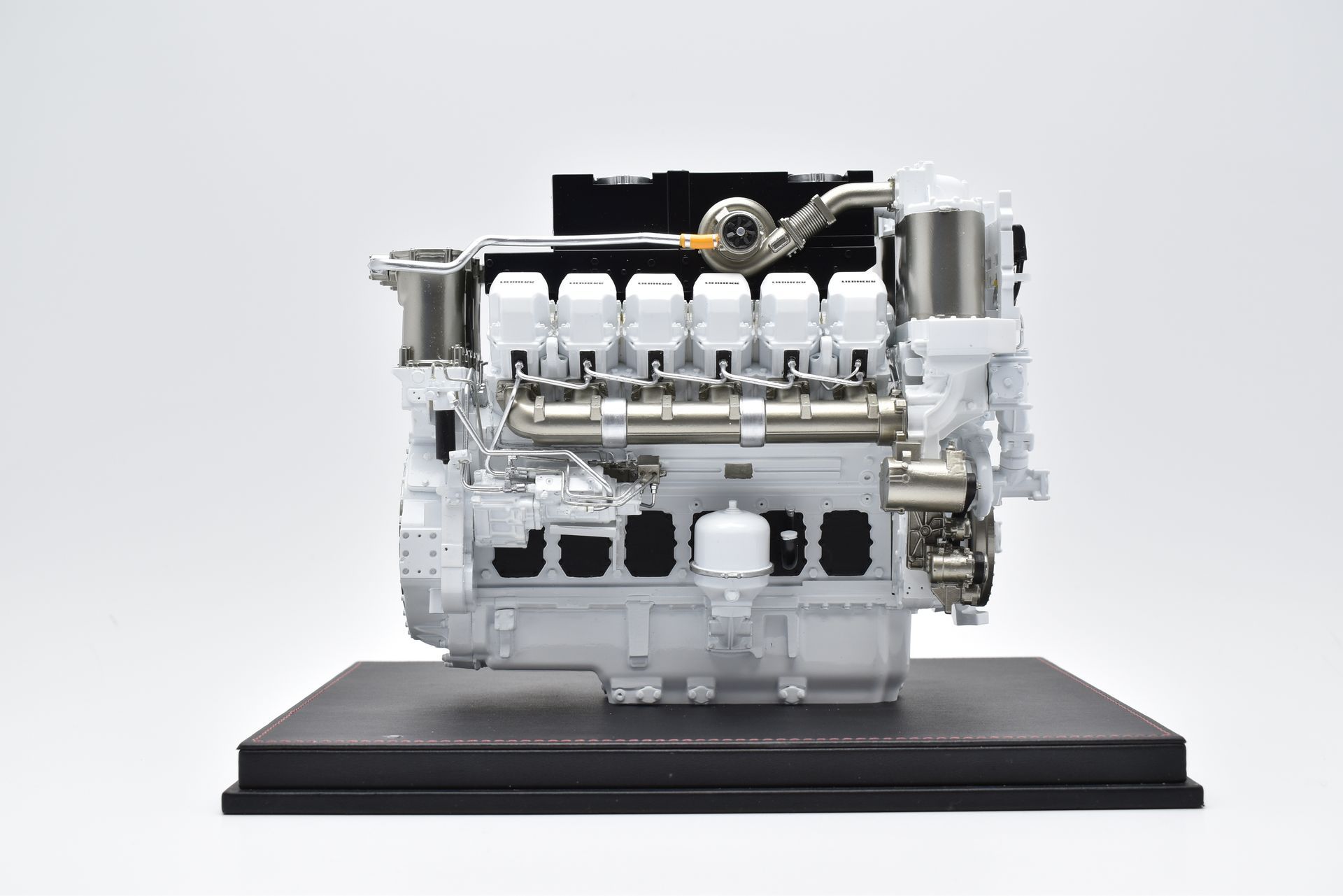 Witte industriële motor op een zwart platform tegen een witte achtergrond.
