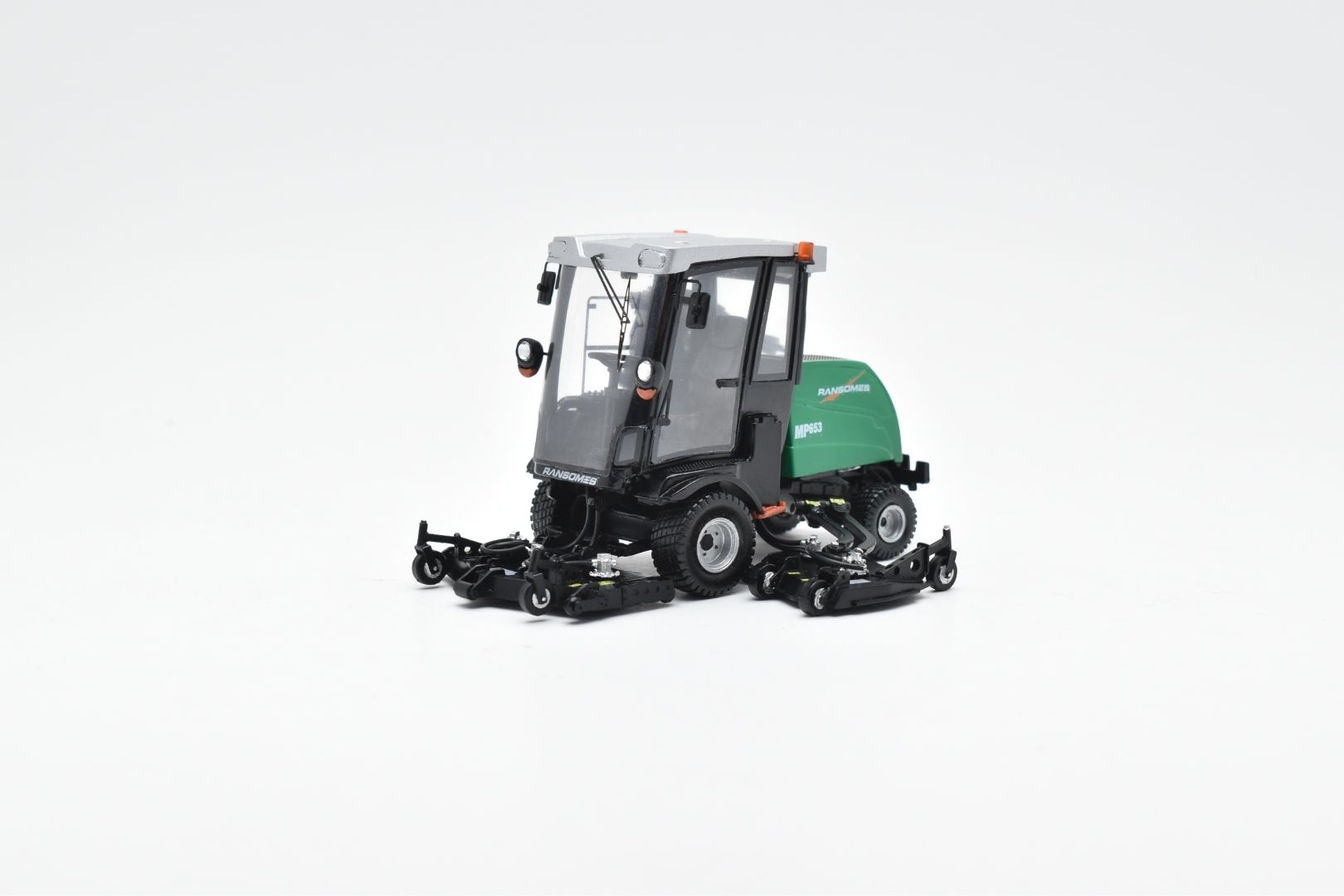 Model van een groen-zwarte grasmaaier met cabine, op een wit oppervlak.