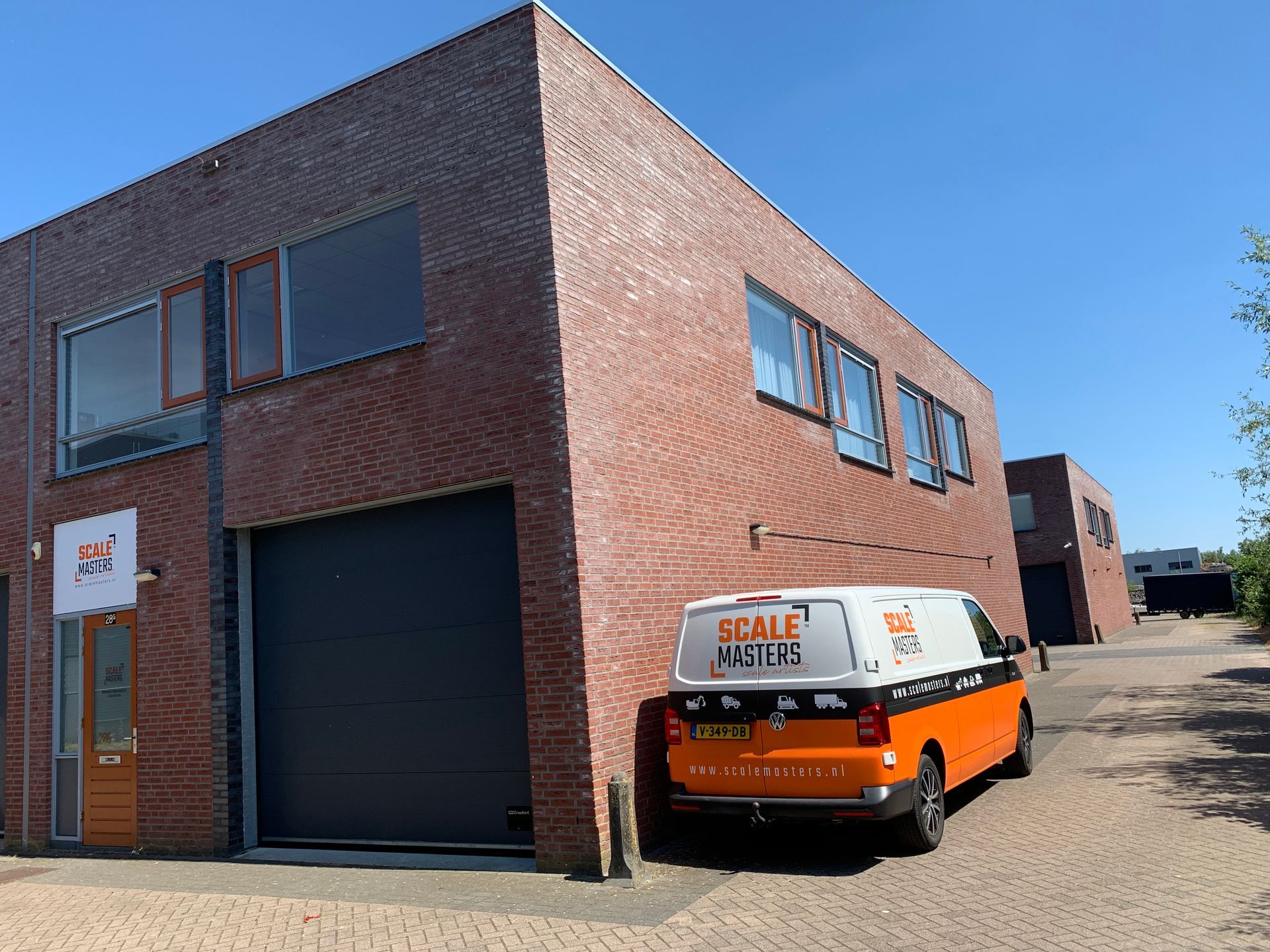 Bakstenen gebouw met een oranje en wit busje ervoor geparkeerd.