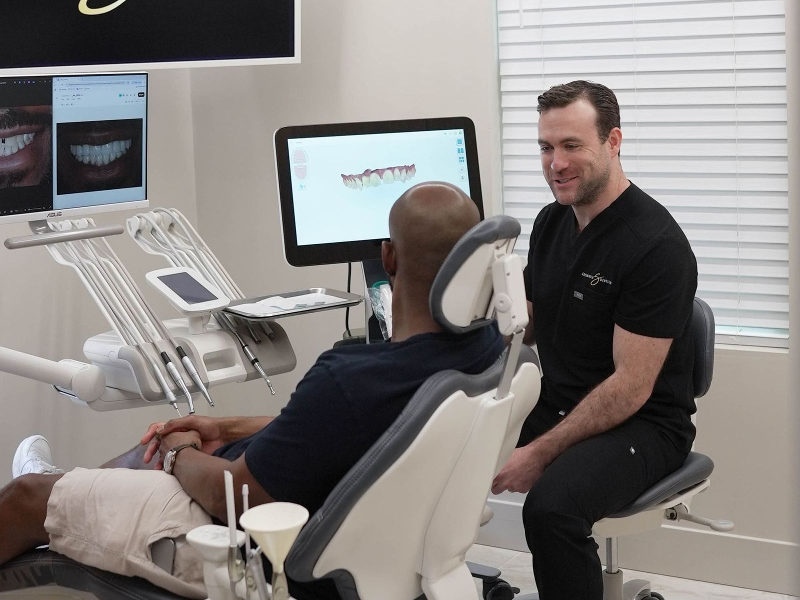 A man is sitting in a dental chair talking to a dentist.