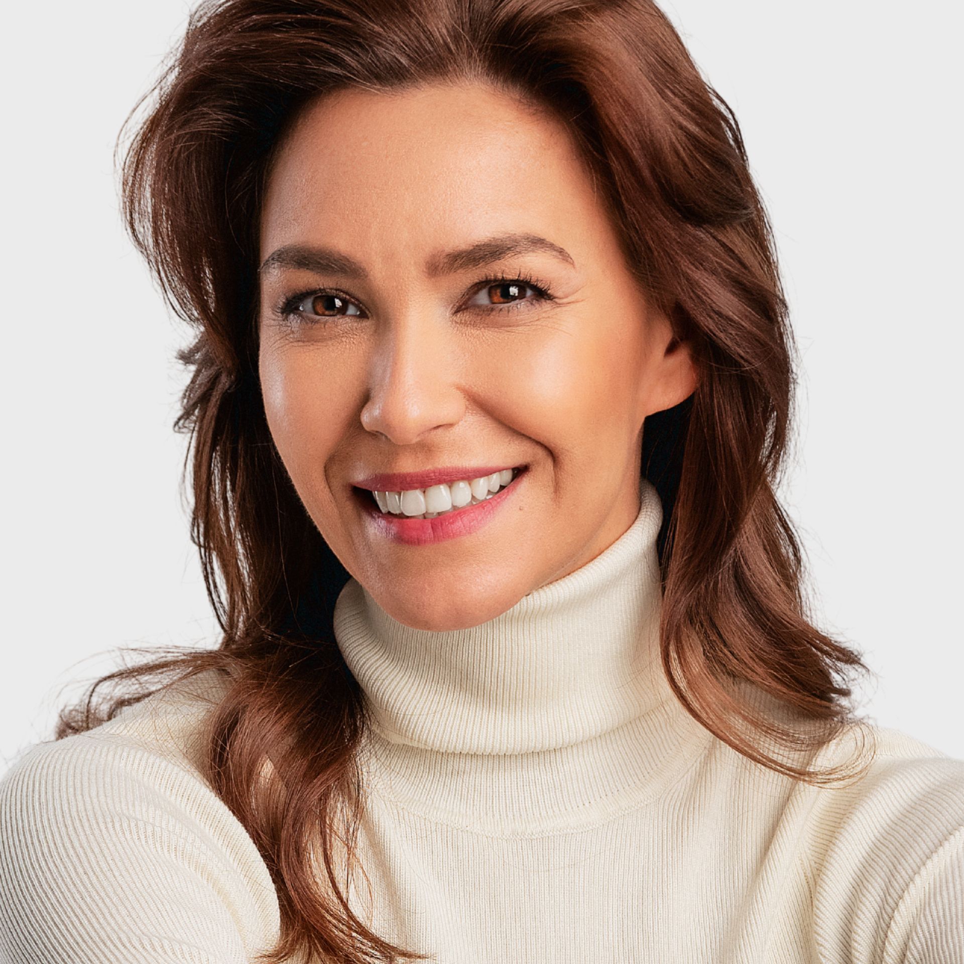 A woman wearing a white turtleneck sweater is smiling.