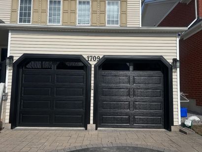 Two glossy black garage doors on a light beige house with the number 1709 displayed above them.