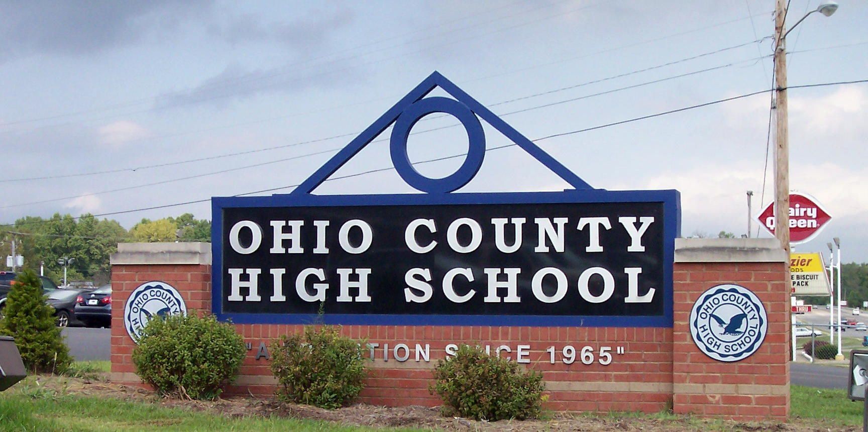 Ohio County High School sign with blue lettering and red brick base outdoors