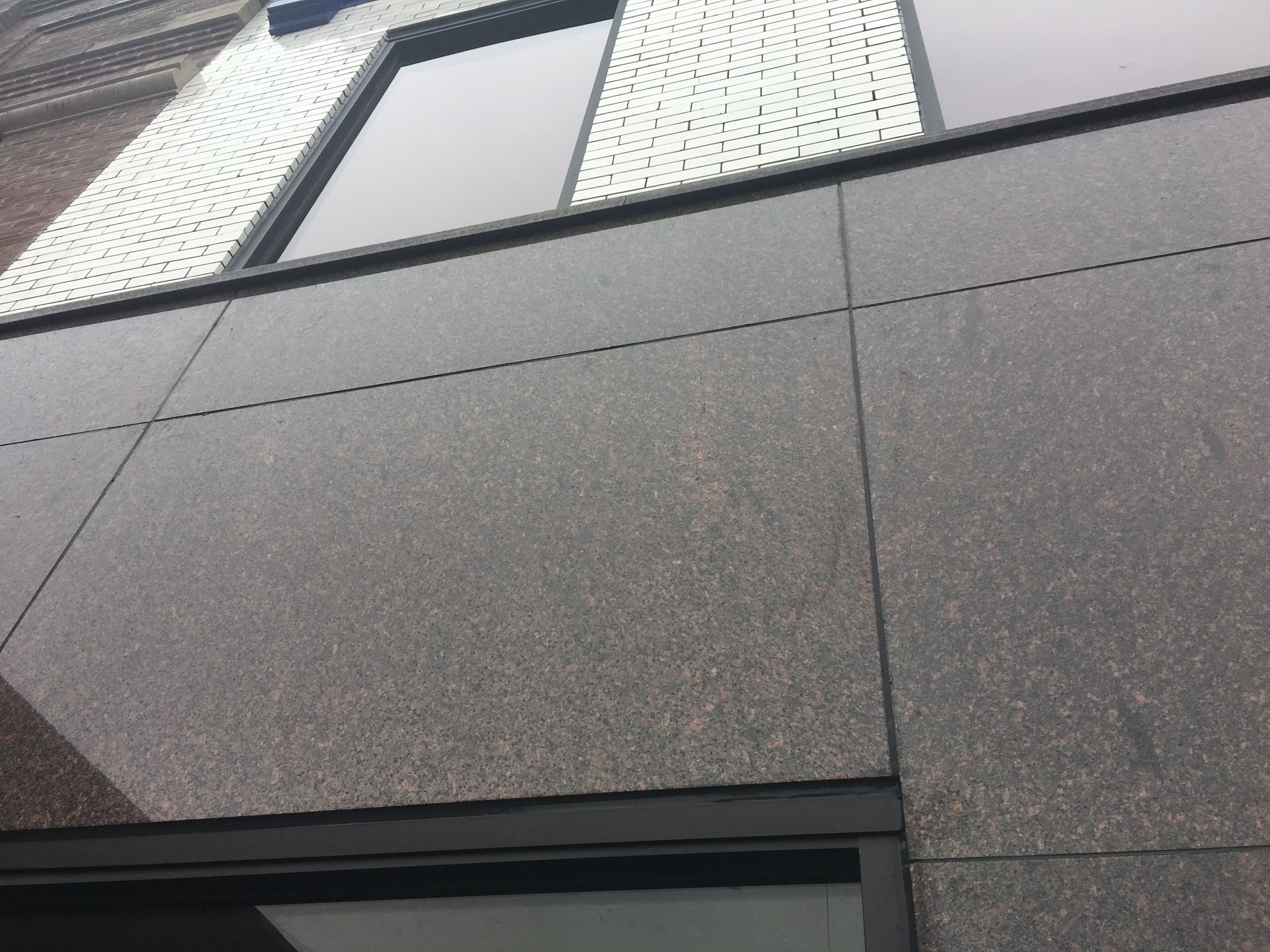 Exterior of a modern building with dark gray paneling and a window above.