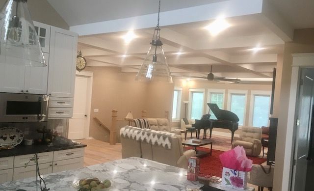 Spacious living room with a grand piano, dining table, and chandelier lighting
