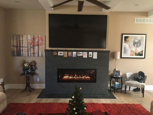 Cozy living room with fireplace, large TV, red rug, and a small decorated Christmas tree.