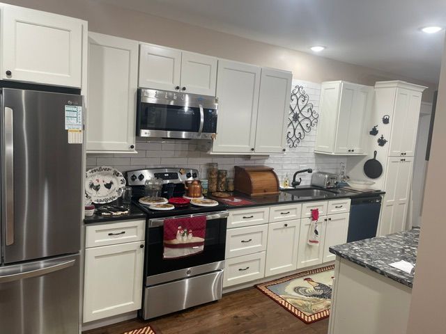 Bright white kitchen with stainless steel appliances, black stove, and patterned countertop decor