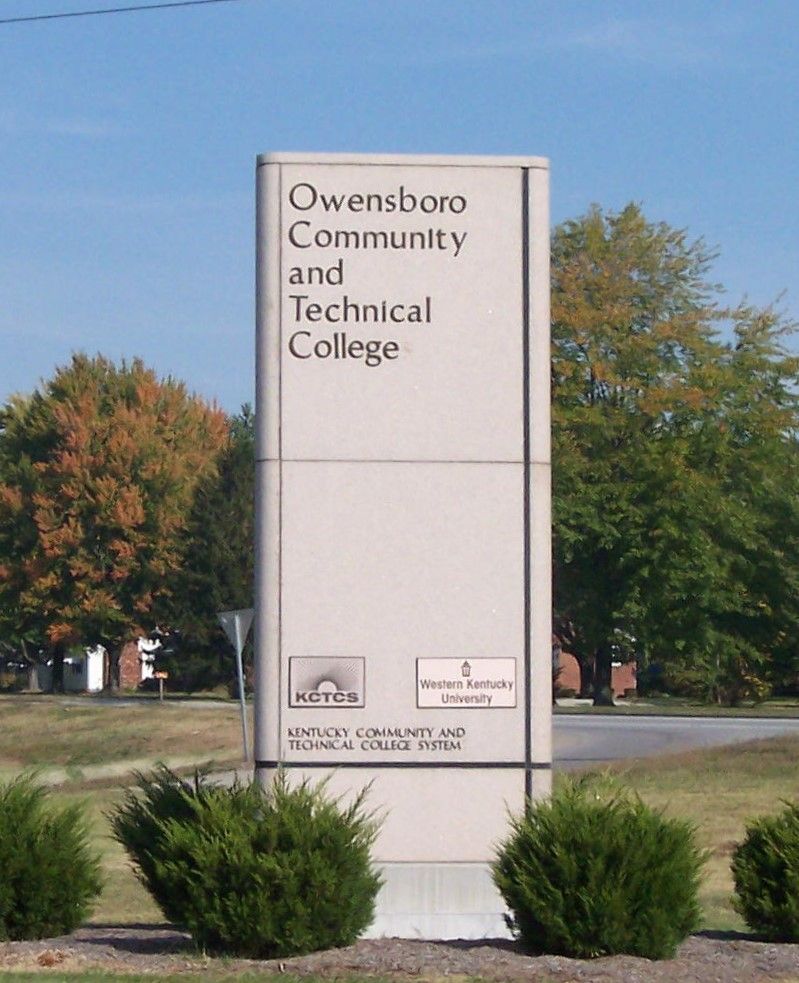 Owensboro Community and Technical College sign beside shrubs and trees outdoors