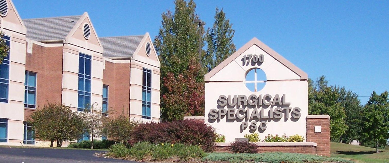 Exterior sign for Surgical Specialists in front of a brick office building and trees
