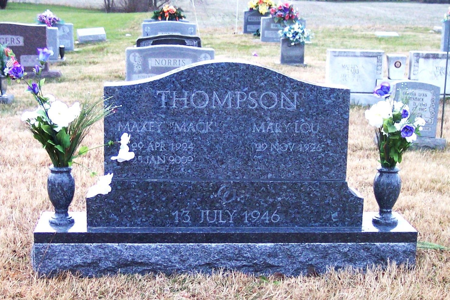 Black granite gravestone with flower vases in a cemetery, engraved with the name Thomson.