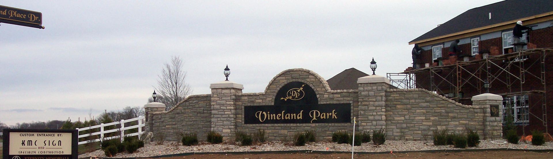 Stone entrance sign reading “Leland Park” with landscaping and a building in the background