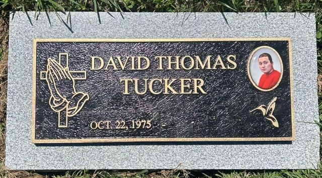 Gravestone plaque for David Thomas Tucker, with dove and portrait medallion on gray stone