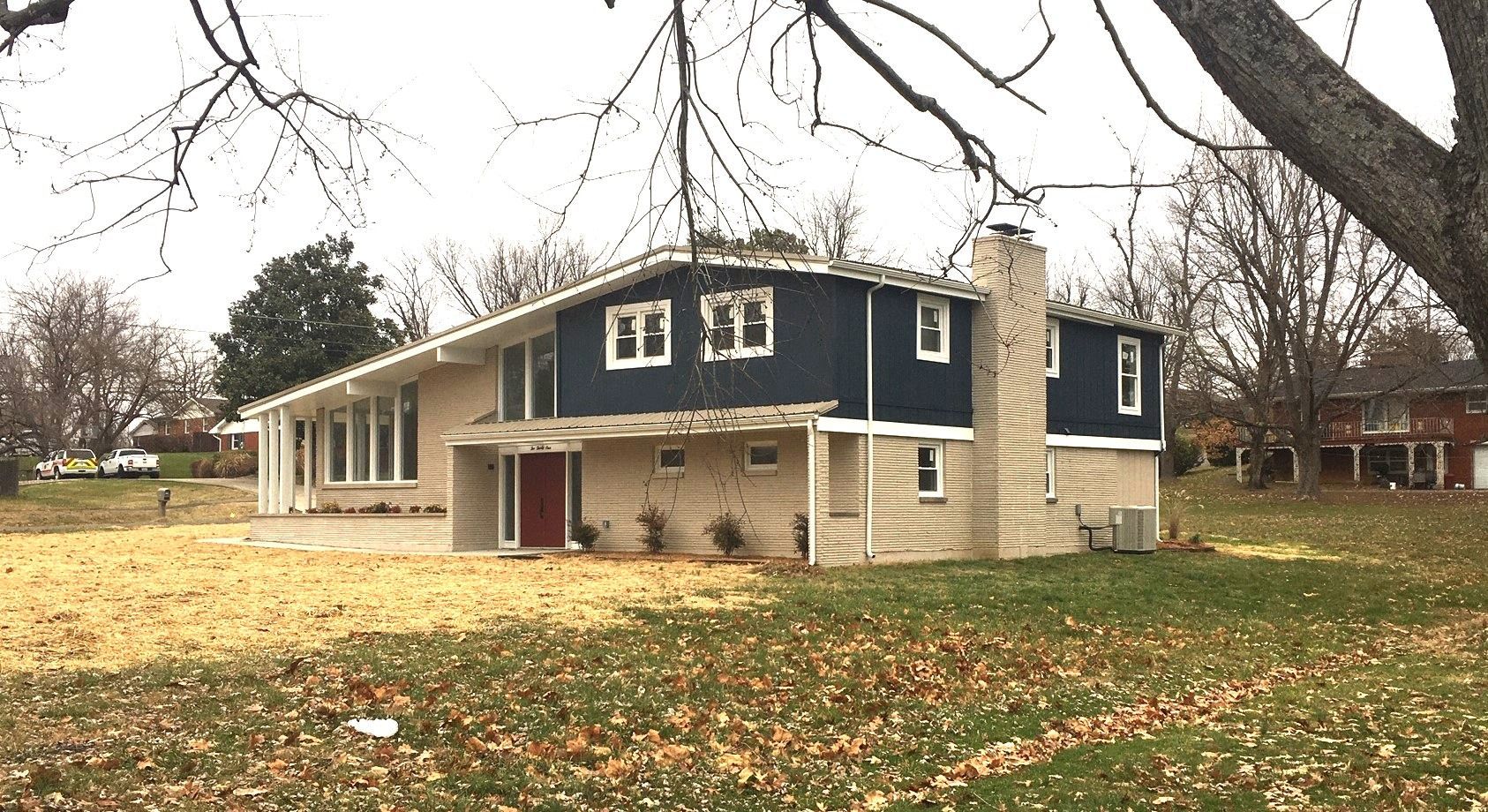 Two-story blue house with beige trim and a large lawn under leafless trees
