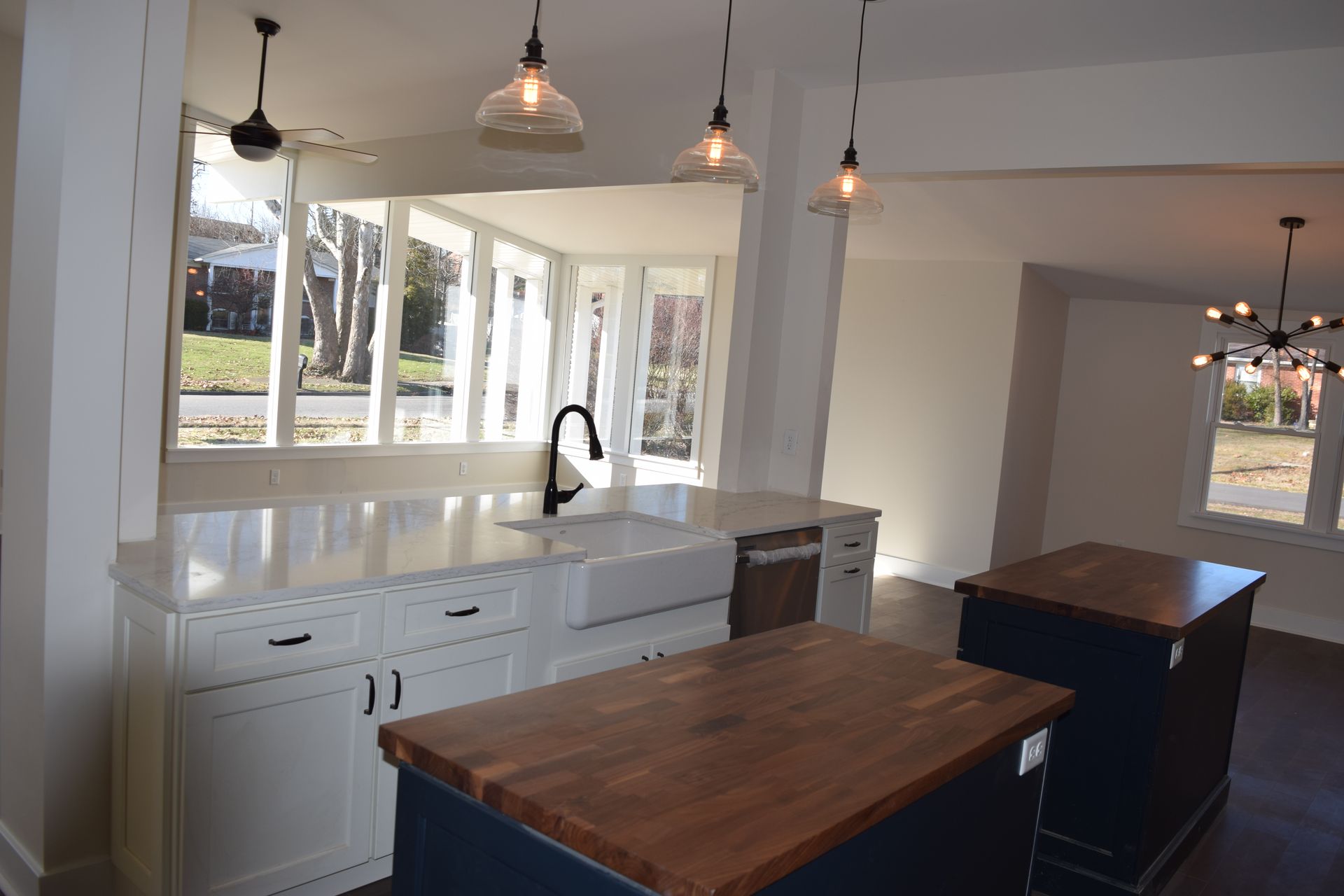 Bright modern kitchen with white cabinets, wood islands, and hanging pendant lights