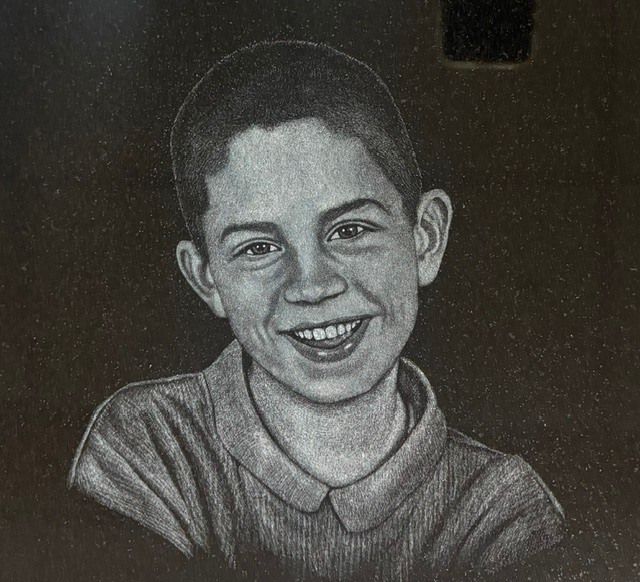 Black-and-white portrait of a smiling person in a collared shirt against a dark background